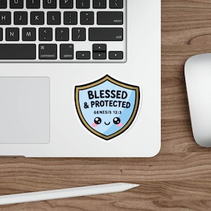 May include: A sticker with a shield design featuring the text "BLESSED & PROTECTED" and "GENESIS 12:3" in blue and white. The sticker has a cute face design with two eyes and a smile. The sticker is on a laptop.
