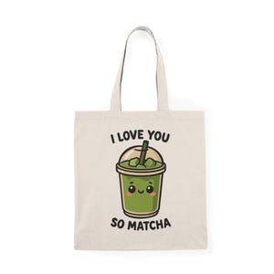 May include: Cream-colored tote bag featuring a cute matcha drink illustration with the text "I LOVE YOU SO MATCHA" in black. The matcha drink has a smiling face and a straw.