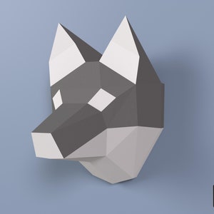 May include: A papercraft model of a wolf's head, made from grey and white paper. The model is assembled and ready to be displayed.