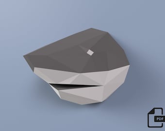 May include: A gray and white papercraft model of a shark's head. The model is made of folded paper and has a three-dimensional appearance.