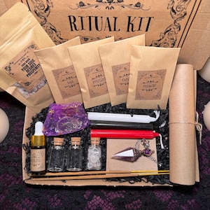 Może przedstawiać: Brązowe kartonowe pudełko z napisem "THE MOONCHILD TAROT UK RITUAL KIT" na górze. Pudełko zawiera różne przedmioty, w tym zioła, świece, kryształy i wahadło. Przedmioty są ułożone w sposób wizualnie atrakcyjny.