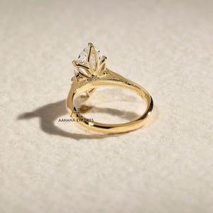 May include: A gold engagement ring with a pear-shaped diamond center stone. The ring features a floral-inspired setting and a delicate band. The ring is shown on a neutral background. The text "AAHANA EXPORTS" is visible.