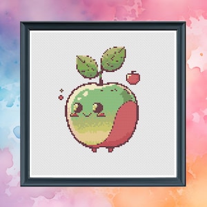 Puede incluir: Un patrón de punto de cruz con una manzana de dibujos animados con un cuerpo verde y rojo, dos hojas y una pequeña manzana roja en la parte superior. La manzana tiene una cara sonriente con dos ojos negros y una boca rosa.