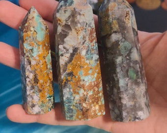 May include: Three green, brown, and white crystal points with a pointed tip. The crystals are different sizes and have a speckled pattern.