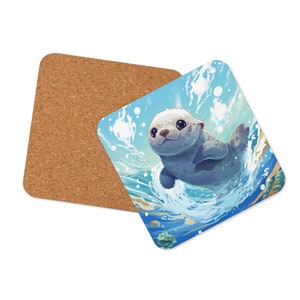 May include: Square coaster featuring a cartoon seal swimming in the ocean. The seal is gray and white with big eyes and a smiling expression. The background is blue with white splashes. A second coaster made of cork is also visible.