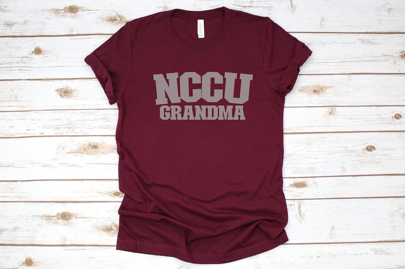 K&ouml;nnte beinhalten: Burgunderfarbenes T-Shirt mit dem Text "NCCU GRANDMA" in grauer Schrift.