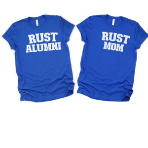 May include: Two royal blue t-shirts with white text. One shirt says "Rust Alumni" and the other says "Rust Mom".