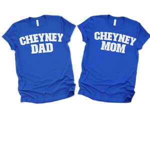 Puede incluir: Dos camisetas azul real con texto blanco. La camiseta de la izquierda dice "CHEYNEY DAD" y la camiseta de la derecha dice "CHEYNEY MOM".