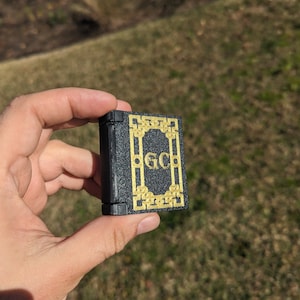 May include: A small black book with a gold border and the initials "GC" on the front.