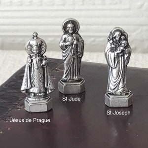 May include: Three silver figurines of saints, each standing on a hexagonal base. The figurines are of St. Jude, St. Joseph, and Jesus de Prague.