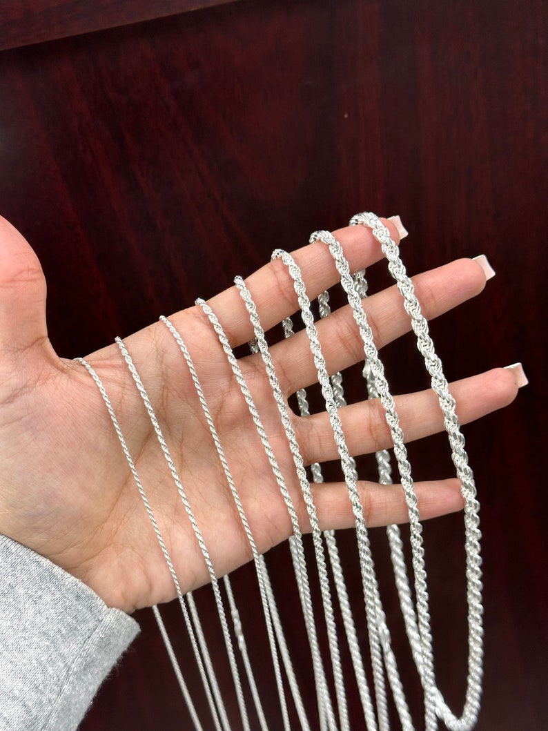 May include: A collection of silver rope chains of varying lengths and thicknesses.