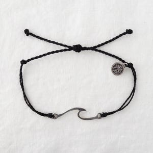May include: Black cord bracelet with a silver wave charm and a silver palm tree charm.