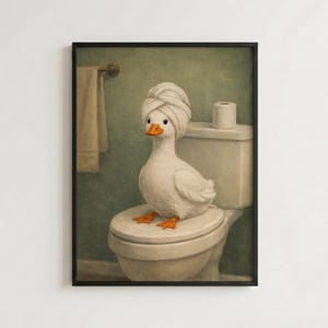 Pode incluir: Uma impressão de arte de parede emoldurada retratando um pato branco com bico e pés laranja sentado num vaso sanitário branco. O pato tem uma toalha branca enrolada na cabeça como um turbante. Uma toalha bege está pendurada num gancho de parede.