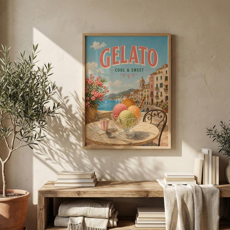 May include: A framed vintage-style print featuring the word "Gelato" in coral lettering. The image depicts a seaside scene with colorful buildings, a table with ice cream, and a glass of water. The sky is blue with fluffy clouds.