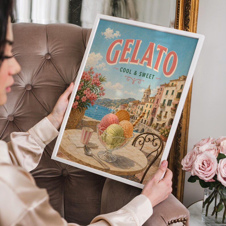 May include: A framed print featuring a vintage gelato advertisement. The artwork showcases a seaside Italian town with gelato in a glass bowl, a table, and the words "Gelato Cool & Sweet" in a retro font.