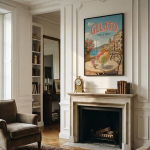 May include: A framed "Gelato Cool & Sweet" poster hangs above a fireplace. The poster depicts a gelato sundae on a table with a coastal Italian town in the background. A gold clock and books sit on the mantel. A brown armchair is in the foreground.