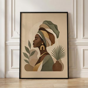 May include: A framed art print featuring a profile of a woman wearing a turban in shades of green, brown, and gold. The artwork includes a vase with a plant and other botanical elements, all in a neutral color palette. The print is in a black frame.