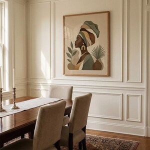 May include: A framed art print featuring a profile of a person wearing a head wrap in shades of green, brown, and yellow. The artwork includes botanical elements and is displayed in a dining room setting with a wooden table and chairs.