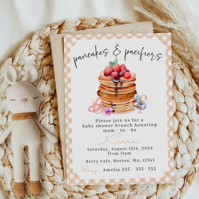 May include: Baby shower invitation with a watercolor illustration of pancakes topped with berries and syrup. The invitation features the text "pancakes & pacifiers" and event details, including the date, time, and location.