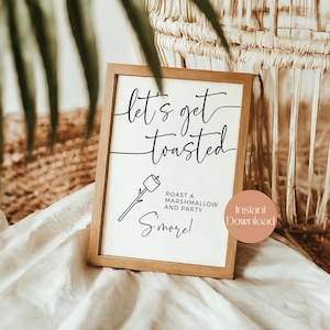 May include: Wooden framed sign with the text "let's get toasted" in a handwritten font. Below the text is a graphic of a marshmallow on a stick, with the words "Roast a Marshmallow and Party S'more!" printed below.