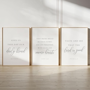 May include: Three framed prints with inspirational quotes from the Bible. The first print says "Give us this day our daily bread" with the reference "Matthew 6:11". The second print says "They broke bread in their homes and ate together with glad and sincere hearts" with the reference "Acts 2:46". The third print says "Taste and see that the Lord is good" with the reference "Psalm 34:8".