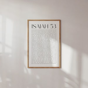 Może przedstawiać: Wydrukowany i oprawiony fragment Księgi Izajasza 53 z Biblii. Tekst jest w czarnym kolorze na białym tle. Rama jest w jasnym kolorze drewna.