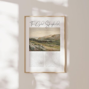 May include: A framed wall art print titled The Good Shepherd in black script, featuring a landscape painting of a grassy hillside with sheep and a distant body of water, accompanied by a block of printed text below the image in a serif font.
