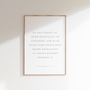 May include: A framed print with a white background and black text. The text reads: "DO NOT FORGET TO SHOW HOSPITALITY TO STRANGERS, FOR BY SO DOING SOME PEOPLE HAVE SHOWN HOSPITALITY TO ANGELS WITHOUT KNOWING IT." The text "HEBREWS 13:2" is at the bottom.