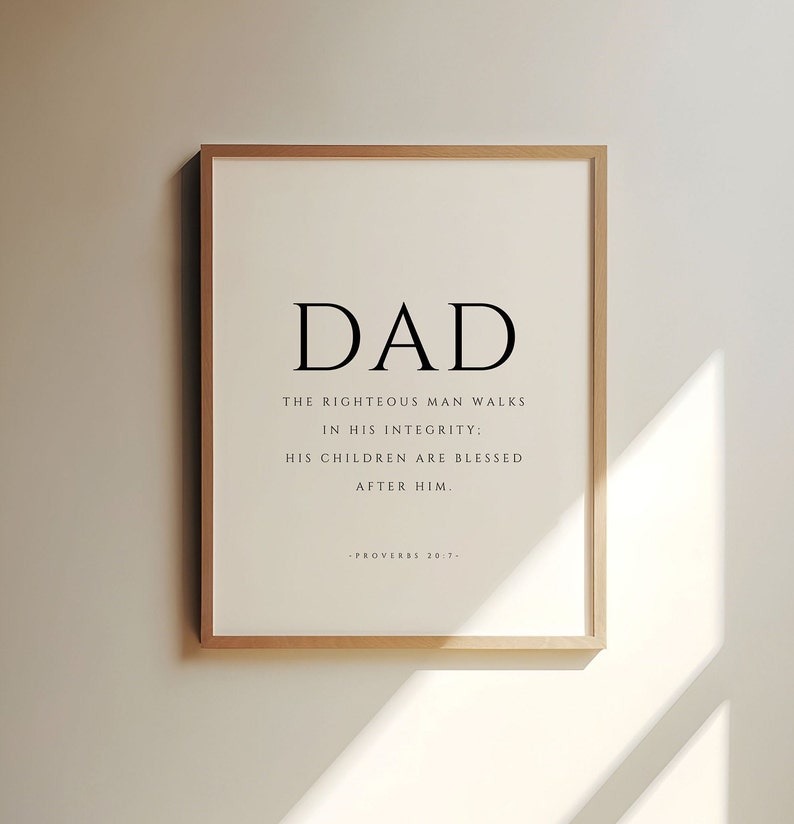 Puede incluir: Una impresi&oacute;n enmarcada con un dise&ntilde;o en blanco y negro. El texto dice "DAD" en letras grandes, seguido de la cita "El hombre justo camina en su integridad: Sus hijos son bendecidos despu&eacute;s de &eacute;l." La cita se atribuye a Proverbios 20:7.