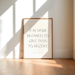 May include: A framed print with the quote "It is more blessed to give than to receive" and the scripture reference "Acts 20:35". The print is on a white background with black text and is framed in a light wood frame.
