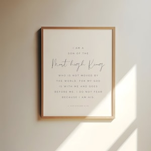 Op de afbeelding: Een witte ingelijste print met een zwart-wit inspirerend citaat. Het citaat luidt "Ik ben een zoon van de Allerhoogste Koning die niet door de wereld wordt bewogen. Want mijn God is met mij en gaat voor mij uit. Ik vrees niet, want ik ben van Hem." Het citaat wordt toegeschreven aan 1 Korintiërs 8:18.