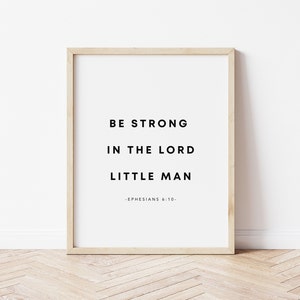 May include: A framed print with the text "Be strong in the Lord little man - Ephesians 6:10 -" on a white background. The frame is light brown wood.