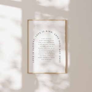 May include: A black and white printable wall art print with a gold frame. The print features a circular design with the text "Love is patient, love is kind, love does not envy" and a list of characteristics of love.