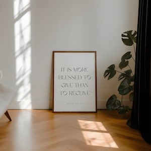 May include: A framed print with a white background and black text that reads "It is more blessed to give than to receive. Acts 20:35". The frame is brown wood.