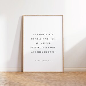May include: A white framed print with a black and white text quote from Ephesians 4:2. The quote reads "Be completely humble & gentle; be patient, bearing with one another in love."