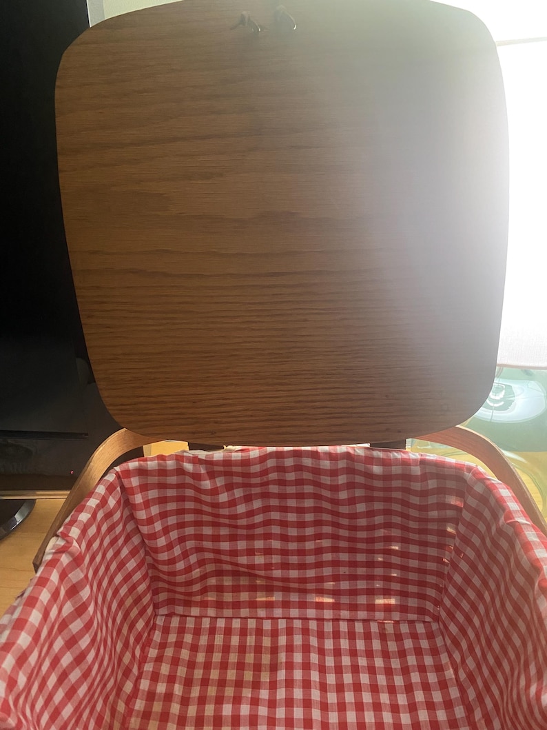 May include: A wooden picnic basket with a red and white gingham lining. The lid is open and the basket is empty.