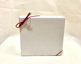 May include: A white gift box with a red ribbon tied around it.