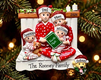 May include: A Christmas tree ornament featuring a family of four and a dog in red and white pajamas. The figures wear Santa hats labeled Dad, Mom, Spencer, William, and Gibson. A green book titled Twas the Night is held, with 2026 and The Rooney Family printed.