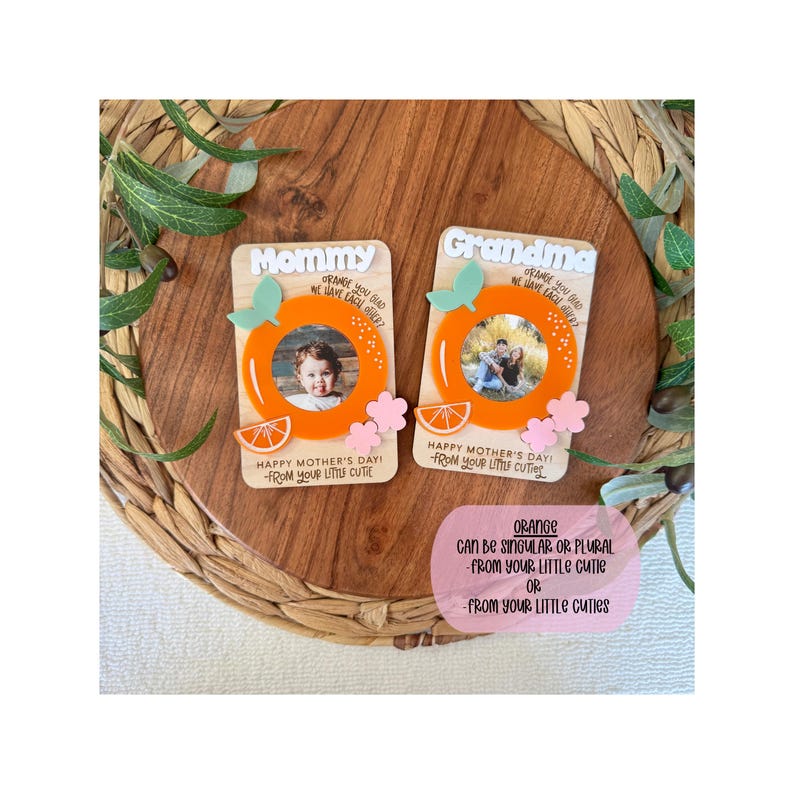 May include: Two wooden Mother's Day photo frames with orange accents. One says "Mommy" and the other "Grandma." Each frame has an orange circle, a photo, and the text "Happy Mother's Day! From your little cutie."