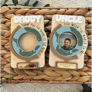 May include: Two wooden photo frames with a globe design. One says "Daddy" and "Thank You For Giving Us The World!" The other says "Uncle" and "You Mean The World To Me!" Both have "World's Best" plaques.