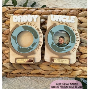 May include: Two wooden photo holders with globe designs. One says "Daddy" and the other "Uncle" in white letters. Each has a small plaque that reads "World's Best Dad" and "World's Best Uncle". The text "Thank you for giving us the world!" is also visible.