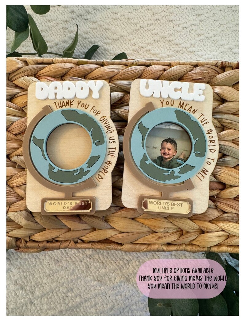 May include: Two wooden photo holders with globe designs. One says "Daddy" and the other "Uncle" in white letters. Each has a small plaque that reads "World's Best Dad" and "World's Best Uncle". The text "Thank you for giving us the world!" is also visible.