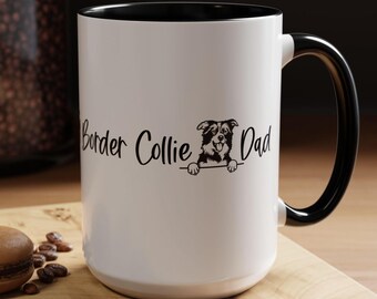 May include: White ceramic mug with a black rim and handle. The mug features a black and white illustration of a Border Collie peeking over the top of the mug. The text "Border Collie Dad" is printed on the mug.