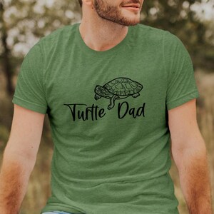 May include: A green t-shirt with a black turtle graphic and the text "Turtle Dad" printed on the front.