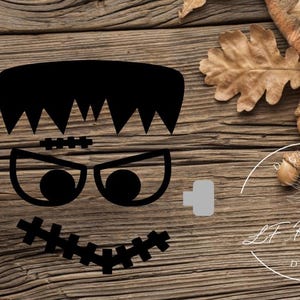 May include: A black vinyl decal featuring the stylized face of a monster with a flat-top haircut, a stitched forehead scar, large eyes with dark pupils, and a wide mouth with a stitched line across it, flanked by two light gray neck bolts.