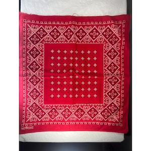 May include: Red bandana with a white geometric pattern border and a central square design. The bandana features a repeating diamond and paisley pattern. The text "FAST COLOR 100% COTTON" is visible in the lower left corner.