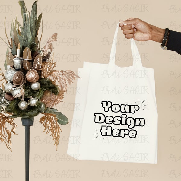 Eco-Friendly Tote Bag Mockup Held by Hand - Neutral Background with Festive Floral Arrangement for Ethical Fashion Displays