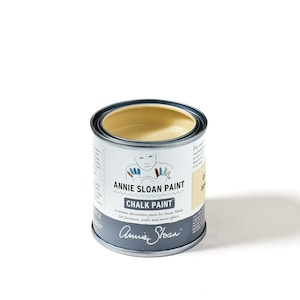 May include: A can of Annie Sloan Chalk Paint in Old White. The paint is a creamy white color and the can has a black label with the Annie Sloan logo and product information.