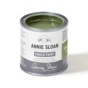 May include: A round metal paint can filled with green chalk paint. The label reads "ANNIE SLOAN CHALK PAINT" and "CAPAS GREEN". The can is open, revealing the paint inside. The paint is designed for furniture, walls, and paint effects.