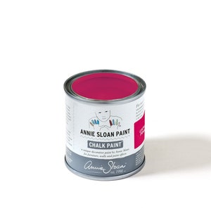 May include: A can of Annie Sloan Chalk Paint in the color Capri Pink. The can is silver with a white label that says "Annie Sloan Paint Chalk Paint" and "a unique decorative paint by Annie Sloan for furniture, walls and paint effects". The label also has a small illustration of a child with painted hands. The bottom of the label says "Annie Sloan est. 1990 - ".